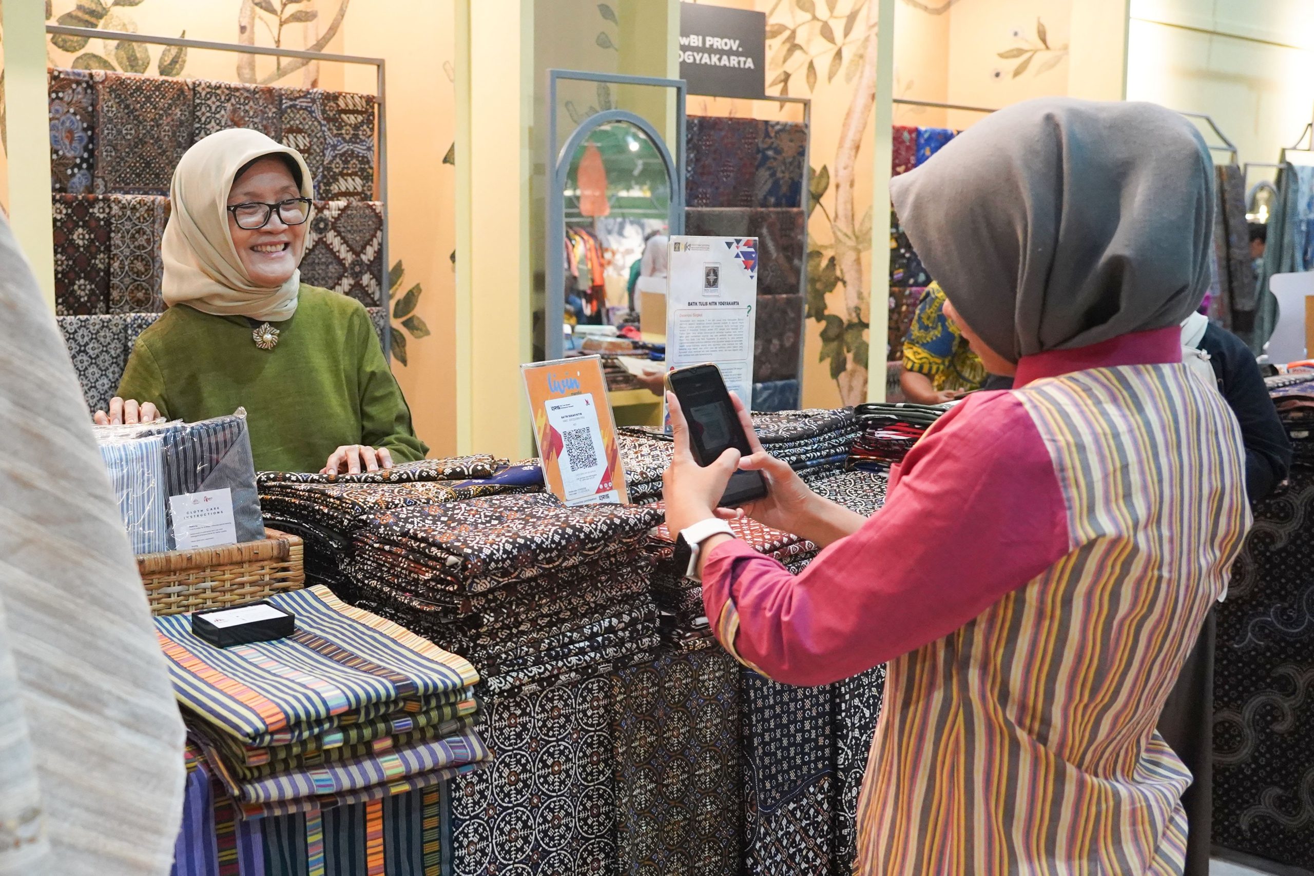 Petugas menunjukkan kode QRIS di kasir toko untuk pembayaran digital