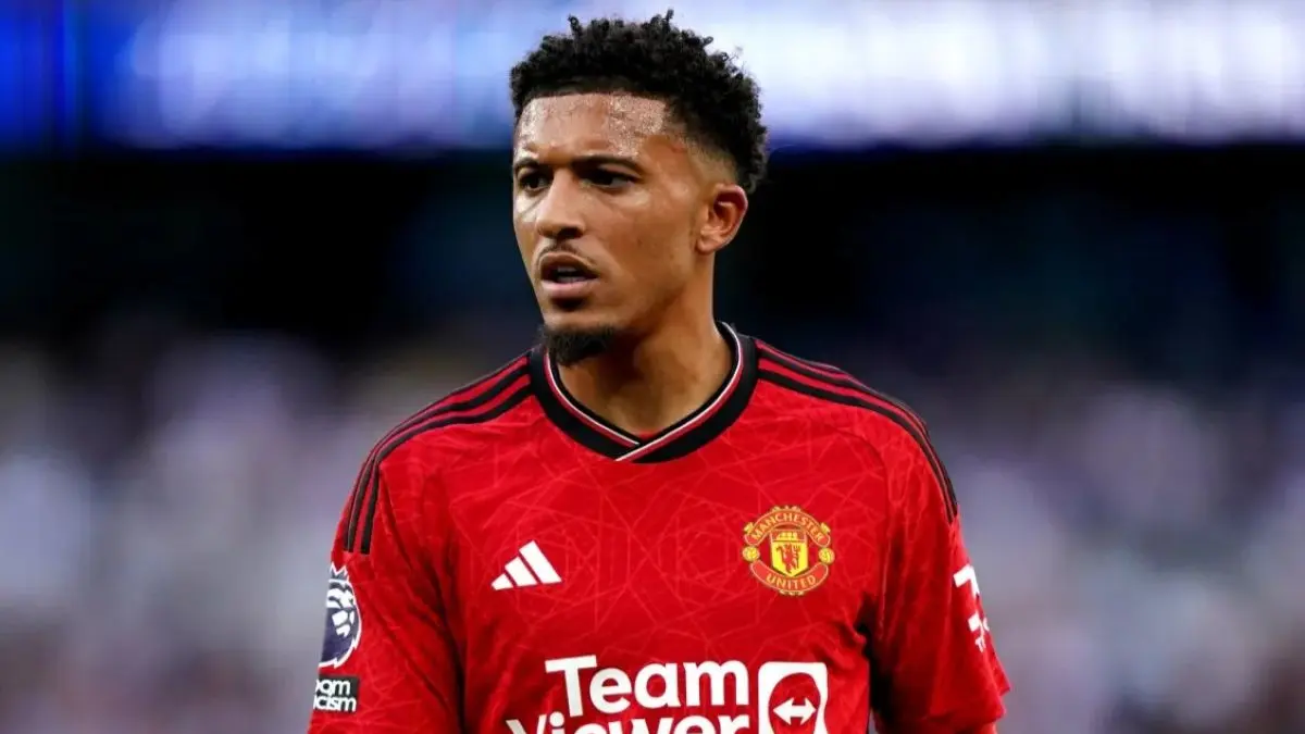 Jadon Sancho berdiri di lapangan hijau mengenakan jersey tanpa logo klub, melambangkan status bebas transfernya.